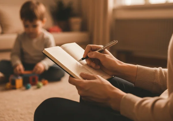 Parent observing child and taking notes in a notebook